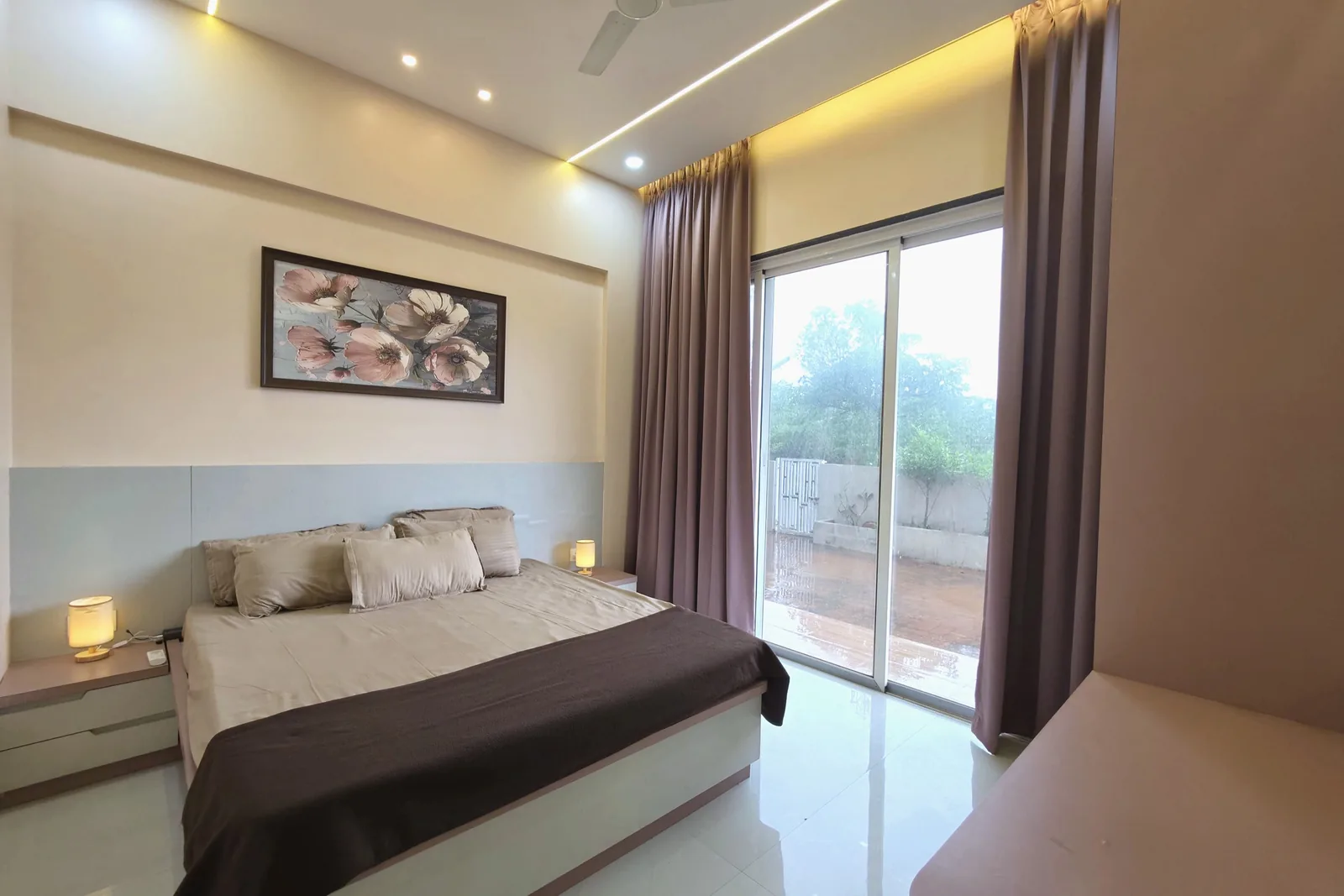 A bedroom with a double bed, padded headboard and glass doors to the balcony.